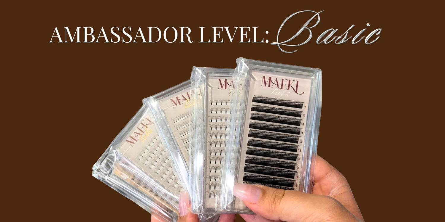 Hand holding a set of false eyelashes with 'Ambassador Level: Basic' text on a brown background